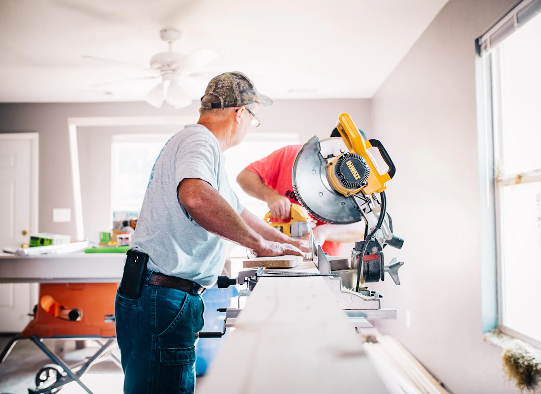 Maintenance worker cutting a board indoors