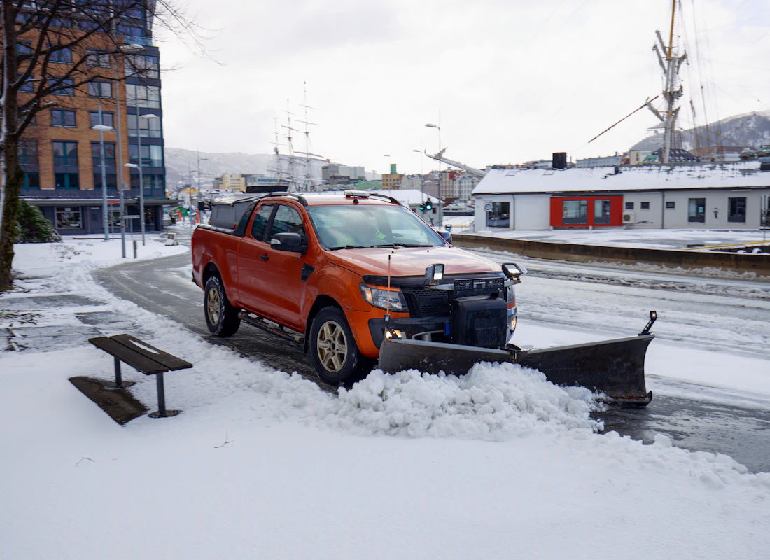 Pickup truck with a plow clearing a residential street